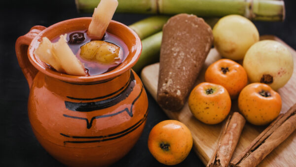 Ponche navideño: jarro de barro con ponche, tejocotes, manzanas y caña de azúcar